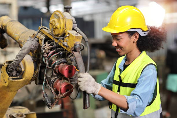 Professional heavy industry technician engineer in safety workwear repairing part of broken robot arm machine in intelligent factory automotive. Industrial and technology support system concept