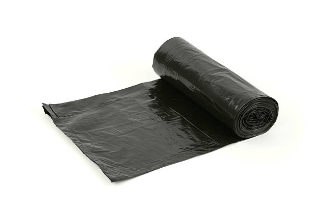 Roll of new black trash bags, isolated on white.