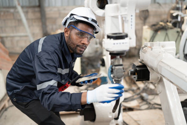 Afriacan American technician engineer man use tablet computer control with checking machine arm robot at factory