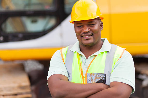 smiling african mine worker with arms folded at mining site